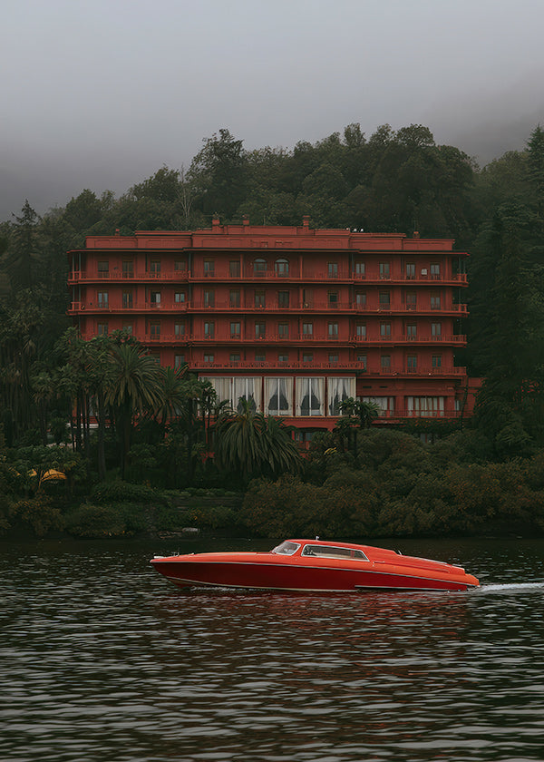 Landschapsschilderij met rood hotel en speedboot